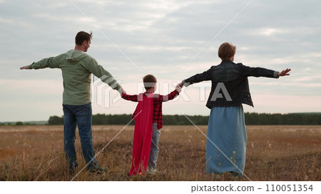 Positive family stretches out arms to sides simulating flight in dry field 110051354