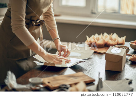 women's hands pack cupcakes into a craft box. concept of food delivery. Birthday package. small business. Bakery chef baking pastry and cake in the kitchen women's hands pack cupcakes into a craft box. concept of food delivery. Birthday package. small business. Bakery chef baking pastry and cake in the kitchen 110051777