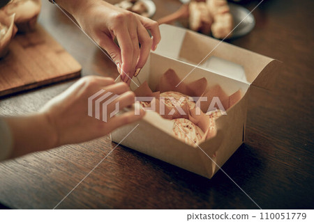Close up women's hands pack cupcakes into a craft box. The concept of food delivery 110051779