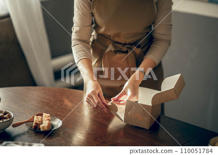 women's hands pack cupcakes into a craft box. The concept of food delivery. Birthday package. small business women's hands pack cupcakes into a craft box. The concept of food delivery. Birthday package. small business 110051784