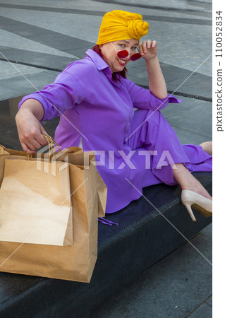 woman with craft shopping bags in the city. The concept of fashionable Consumerism and ecology.  110052834
