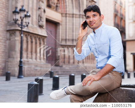 Modern guy walks in city and communicates on smartphone 110053176