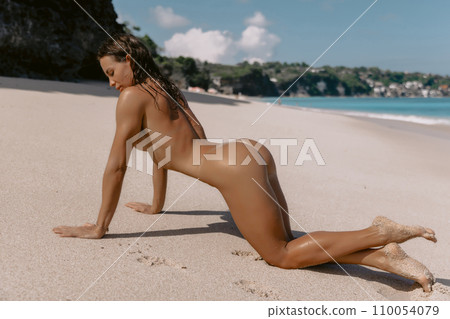 Woman with tanned sporty body relaxing on ocean beach. Sexy model enjoying at tropical beach Woman with tanned sporty body relaxing on ocean beach. Sexy model enjoying at tropical beach 110054079