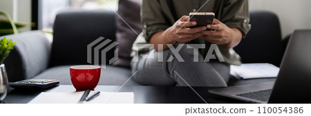 Asian casual businesswoman sits on couch to reading growth finance new startup report on smartphone 110054386