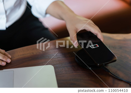 Hands of businessman putting smartphone on wireless charger device to charging battery mobile phone 110054410