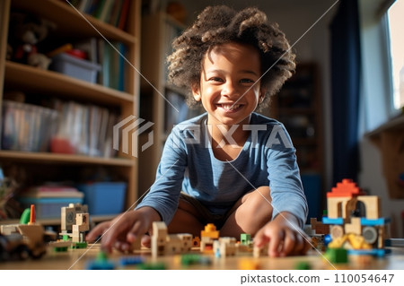 AI-generated content. A little African American boy sits at the table in his cozy room and plays with a construction set. Happy smart kid assembling a model of toy city with houses, cars and people 110054647