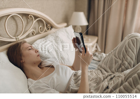 Young woman at home indoor lying on bed in bedroom with digital tablet Young woman at home indoor lying on bed in bedroom with digital tablet 110055514