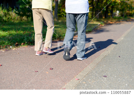 Active senior couple walking for health. Shadows extending from their feet. Diet, exercise, walking. Active senior couple walking for health. Shadows extending from their feet. Diet, exercise, walking. 110055887