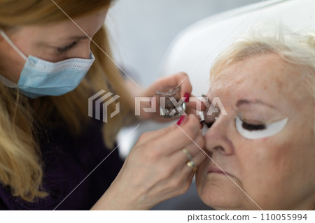 The client waits patiently while the beautician applies the tinting product to her eyelashes. 110055994