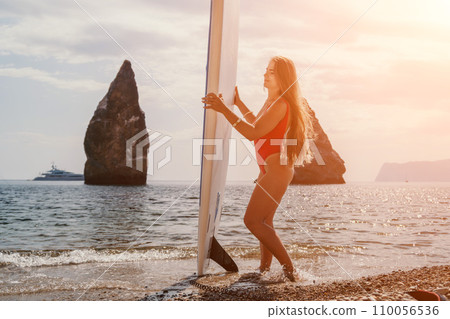 Woman sea sup. Close up portrait of happy young caucasian woman with long hair looking at camera and smiling. Cute woman portrait in bikini posing on sup board in the sea 110056536