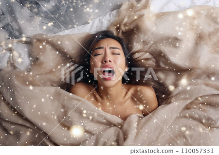 Young asian woman having orgasm. Woman with open mouth and closed eyes enjoying sex lying among flying glitter and sparkles as a symbol of orgasm. Sexual experience, masturbation, cunnilingus. 110057331