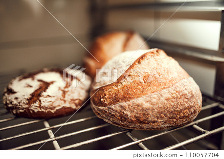 Close up image of different loafs of whole grain bread with golden brown, crispy crust sitting on shelf in bakery shop. Concept of food and nutrition. 110057704