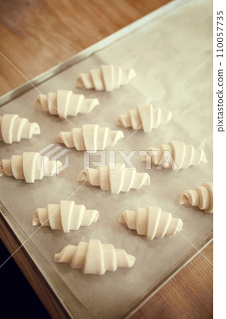 Top view shot, lay out sweet or savory pastries, croissant dough pieces on baking tray covered with parchment. Concept of recipes and cooking. 110057735