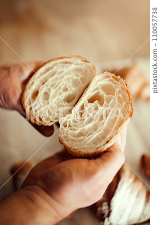 Perfect French pastry. Close up image of baker's hands hold cut croissant and show how perfectly cooked it is. 110057738