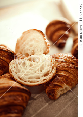 Close up shot plate of golden brown, flaky, buttery crust, warm and delicious croissants and one cut in half. 110057739