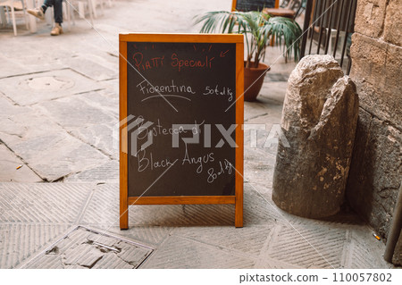 Advertising board of cafe on main streer of old town in Italy. Handwritten Italian restaurant with menu chalkboard. Advertising board of cafe on main streer of old town in Italy. Handwritten Italian restaurant with menu chalkboard. 110057802