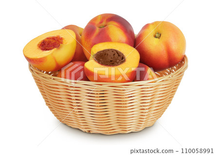 Ripe nectarine fruit with half in a wicker basket isolated on white background with full depth of field 110058991