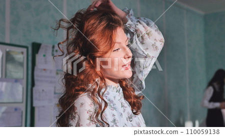 Red-haired girl playing and posing with her hair. 110059138