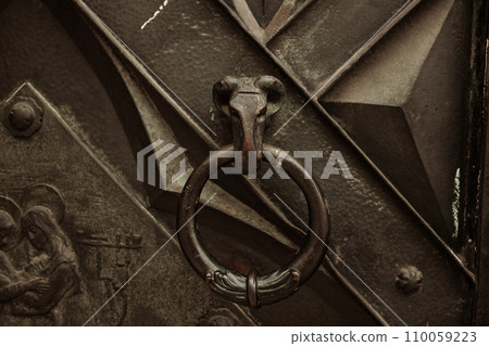 A ram's head knocker on a door, detail of iron door at city street of Krakow A ram's head knocker on a door, detail of iron door at city street of Krakow 110059223