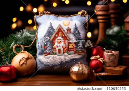 A framed embroidered christmas card with ornaments and candles on wooden table. Winter background with pine twigs 110059253