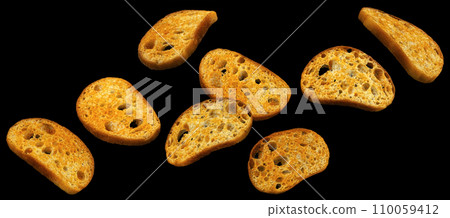 Falling bruschetta crackers, bread croutons on black background Falling bruschetta crackers, bread croutons on black background 110059412