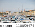 Motor and sailboats are tightly parked in the marina of Marseille against the backdrop of the city. 110059474