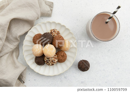 Typical Brazilian sweet brigadeiro. A heap of assorted flavors of candies on a white table Typical Brazilian sweet brigadeiro. A heap of assorted flavors of candies on a white table 110059709