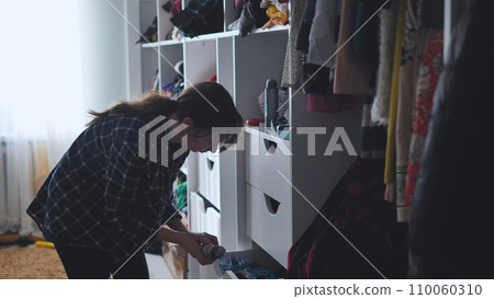 The mother is a housewife looking for clothes in the closet. 110060310