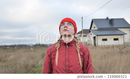 Portrait of a teenage girl in glasses wearing red clothes outside in the fall. 110060321