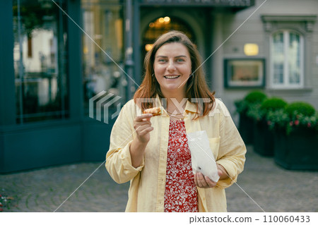Happy woman holding Sicilian cannolo tube pastry filled with cream. Travel, Italy and holidays concept. Young women eating traditional delicious cake cannoli, Traveling Europe in summer Happy woman holding Sicilian cannolo tube pastry filled with cream. Travel, Italy and holidays concept. Young women eating traditional delicious cake cannoli, Traveling Europe in summer 110060433