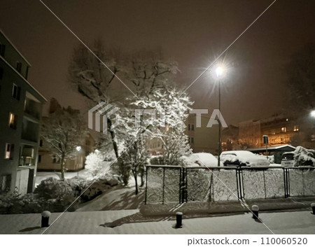 Beautiful winter landscape in the city at night with snow covered trees.Snowy street at night in winter view from the window of a house. Blurred background, bokeh. 110060520