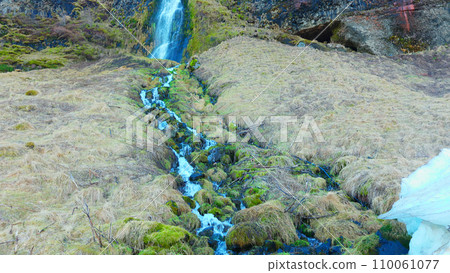 River stream from scandinavian cascade flowing down off of hill, water flow running off cliff in iceland. Beautiful seljalandsfoss waterfall in reykjavik, arctic landscape. Handheld shot. 110061077