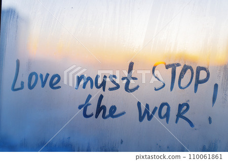 Message Love must stop the war are painted handwriting on blue sunset window with raindrops Message Love must stop the war are painted handwriting on blue sunset window with raindrops 110061861