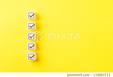 Checklist concept. Correct sign tick check mark on wooden block with copy space for the checklist on yellow background. Business survey questionnaire, Exam test process, filling digital form online, 110063715