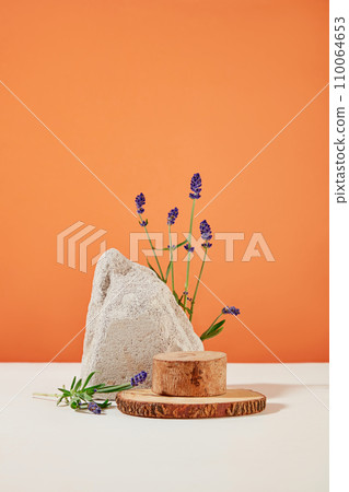 The wooden platform and stone slab are decorated with fresh lavender flowers on a white orange background. Ideal space for displaying products containing lavender extract. 110064653