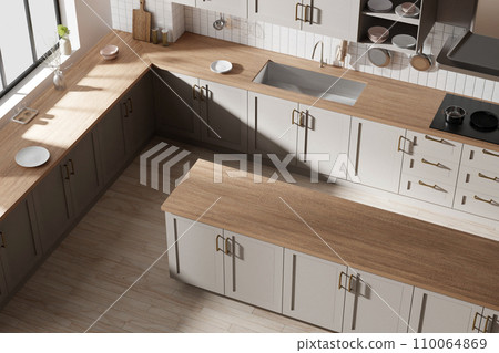 A bright beige-toned kitchen interior with sunlight coming through the window. 110064869