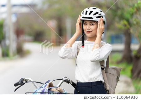 A young woman wearing a cycling helmet and restraining herself with her hands 110064930