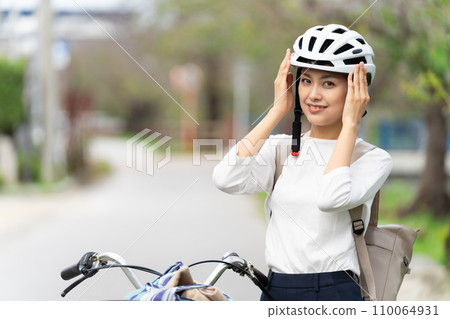 A young woman wearing a cycling helmet and restraining herself with her hands 110064931