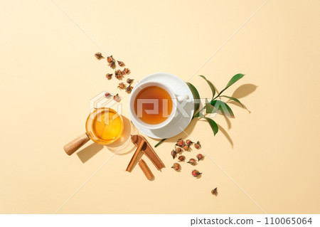 A cup of tea, cinnamon, green tea leaves, herbs and honey on a pastel background. The combination of honey and natural ingredients is very good for health. 110065064