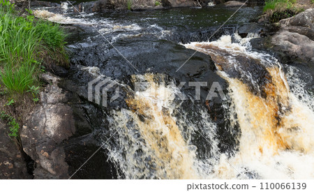 Fast stream water goes over black rocks in a forest. Waterfalls of Ruskeala Fast stream water goes over black rocks in a forest. Waterfalls of Ruskeala 110066139