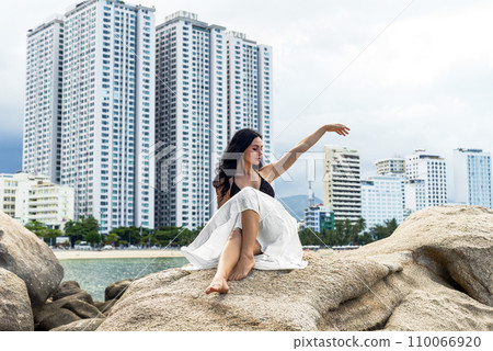 Young ukrainian woman in bikini sitting against cityscape of Nha Trang, Vietnam 110066920