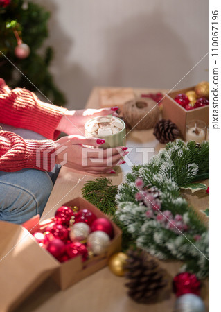 Young asian woman in sweater happiness and drinking hot chocolate with marshmallow after making christmas wreath to preparing ornaments for celebrate christmas festive holiday and winter seasons Young asian woman in sweater happiness and drinking hot chocolate with marshmallow after making christmas wreath to preparing ornaments for celebrate christmas festive holiday and winter seasons 110067196