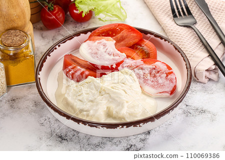 Salad with sliced tomato and stracciatella 110069386