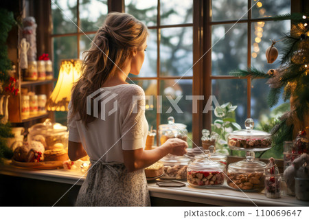 AI-generated content. Nice young woman is standing by the window looking at snow in the cozy Christmas kitchen with sweets 110069647