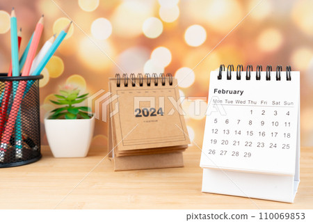 White February 2024 desk calendar on wooden table with gold light bokeh background. White February 2024 desk calendar on wooden table with gold light bokeh background. 110069853