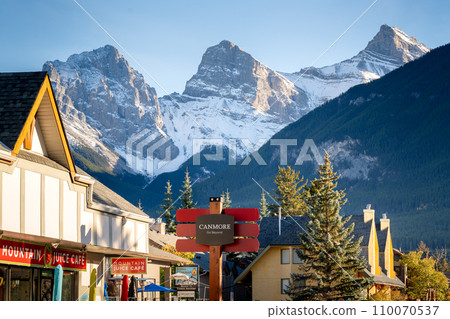 Canmore, AB, Canada - Oct 7 2023 : Canmore Town Sign. The Three Sisters trio of peaks over the blue sky in the background. Canmore, AB, Canada - Oct 7 2023 : Canmore Town Sign. The Three Sisters trio of peaks over the blue sky in the background. 110070537