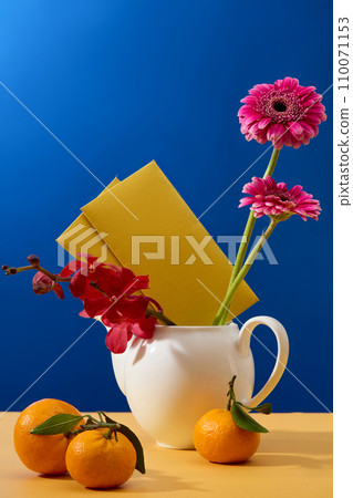 Fresh flowers and lucky money envelopes are displayed along with a ceramic pot and tangerines on the table. Blue background for advertising. Fresh flowers and lucky money envelopes are displayed along with a ceramic pot and tangerines on the table. Blue background for advertising. 110071153