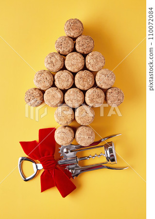 Champagne corks laid out in the shape of a Christmas tree and a metal corkscrew tied with a ribbon on a yellow background Champagne corks laid out in the shape of a Christmas tree and a metal corkscrew tied with a ribbon on a yellow background 110072084