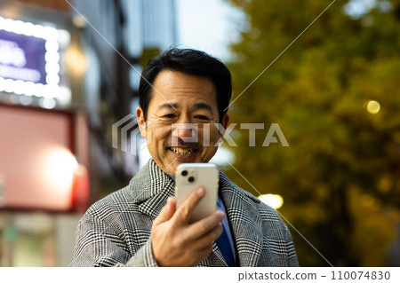 Businessman checking his smartphone on his way home from work 110074830