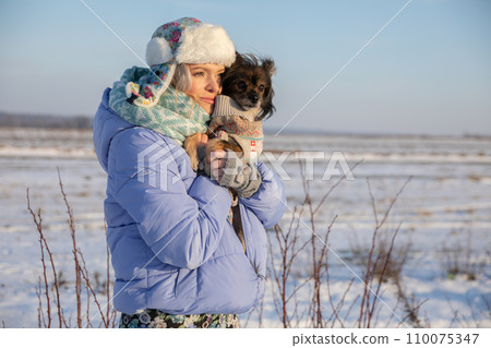 The girl cuddles her face into the fluffy fur of her dog. 110075347